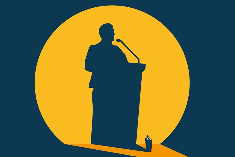 A spotlight illuminates a politician, and his shadow presents an exaggerated version of the character